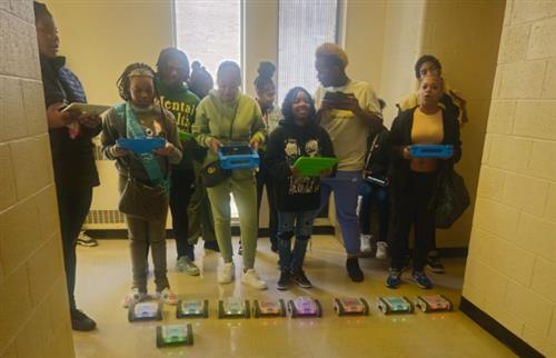 students standing with robot cars controlling them