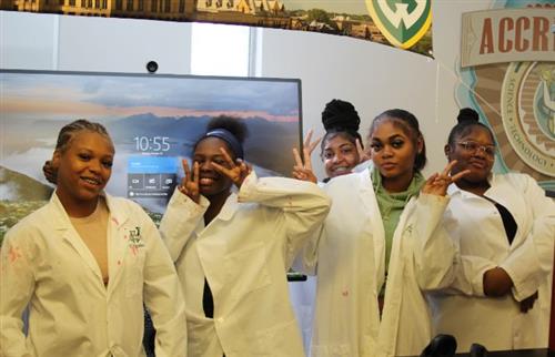 students in lab coats smiling