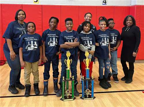 Chryslers award winning 2023 Chess team standing with Mrs. Gray & Principal Shirley