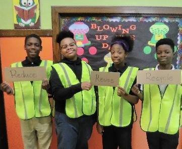 Four students in neon vest holding signs. 