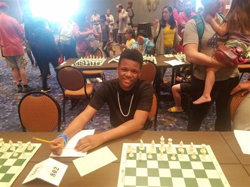 8th grader taking notes at his chess tournament station 