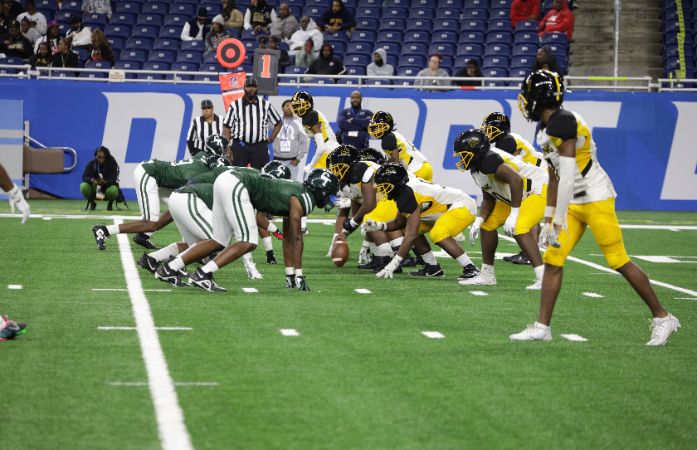MLK and Cass Tech football players on a field in a game.