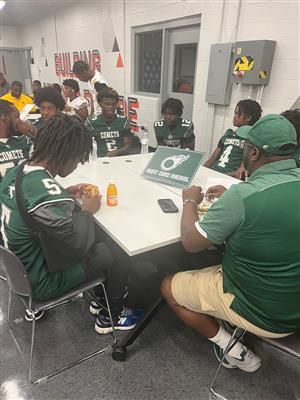 football players and coaches gathered around table