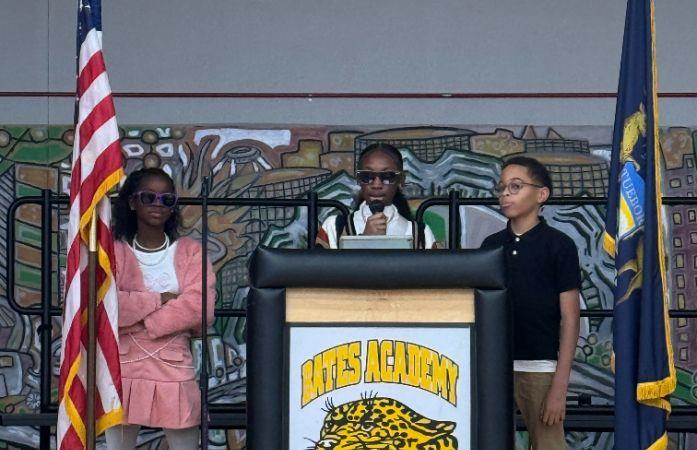  2 girls and 1 boy middle school, on stage with a microphone