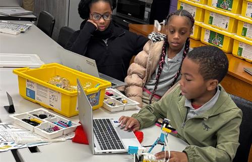 2 girls and boy on a laptop programming a Lego robot