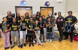 A group of girls and adults posing with trophies in their hands