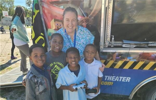 teacher with 4 students outside standing in front of game truck