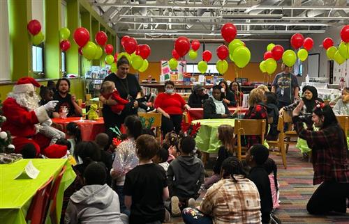 Room with red and green ballons in a room full of people.