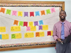  Attendance Agent Mr. Mr. Henry stands next to the attendance wall
