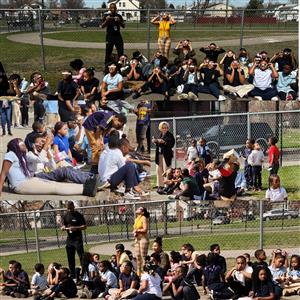 Students sitting on ground  watching the solar eclipse in the sky