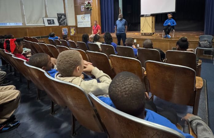  Students sitting and listening to Mr. Rais speak on the importance of attending school.