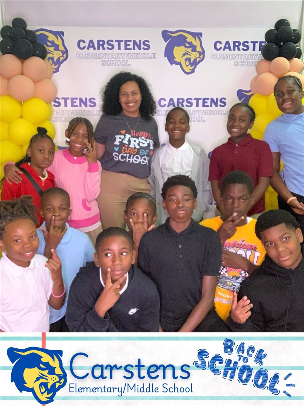  one adult, twelve kids posed for a picture in front a Carstens backdrop. 