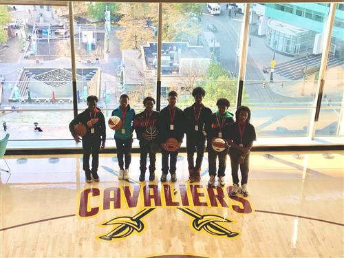 Students holding basketballs on a Cavaliers basketball court. 
