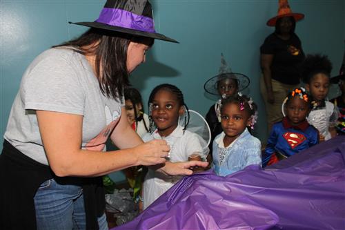 Students line up with teacher to feel what's under the tablecloth. 