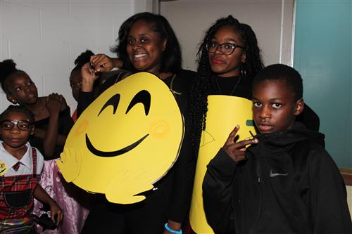 Teachers dressed in emoji costumes pose with student. 