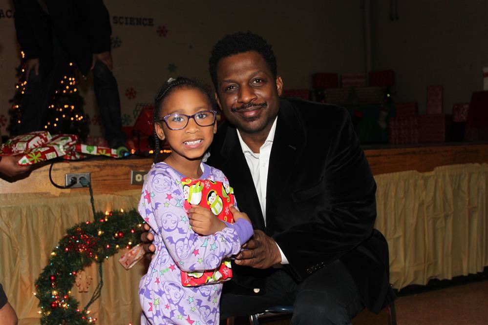 Young girl in pajamas holding a gift with gentleman 