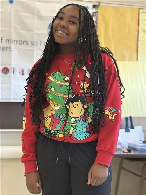 a girl wearing a holiday sweater and smiling for a picture. 