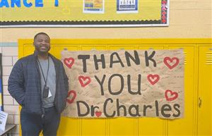  Dr. Charles standing by a sign created by the students