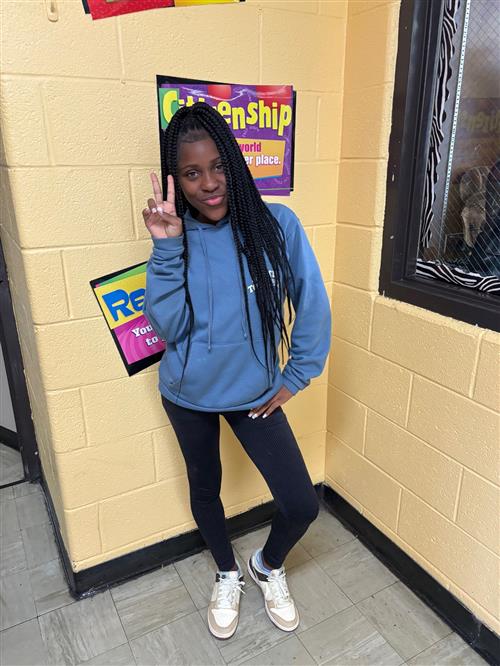 female student standing holding up a peace sign