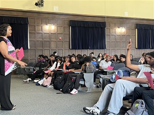 A woman talking to students and one student did raise their hand