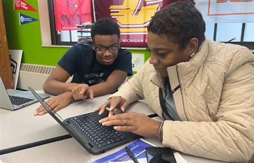The young man is helping the female on the computer