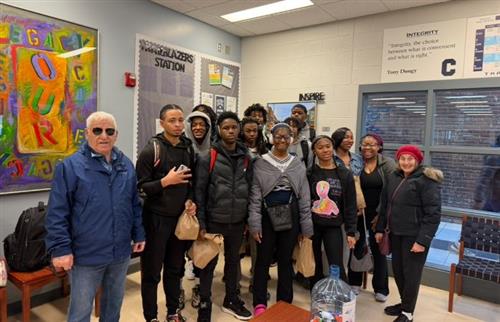 Students standing with the individuals who just delivered the snacks