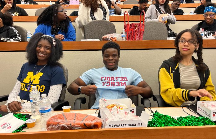  2 girls and 1 boy sitting down smiling