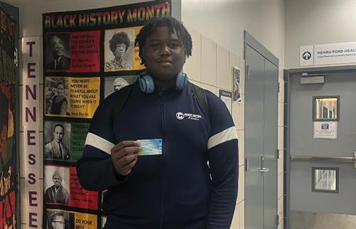  A boy standing holding a card wearing navy blue