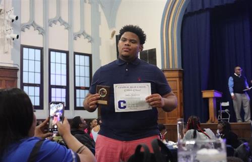 a student holding a paper and medal