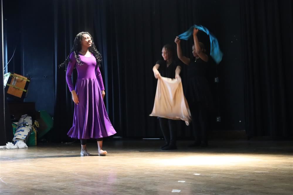  a girl standing and 2 girls waving fabric