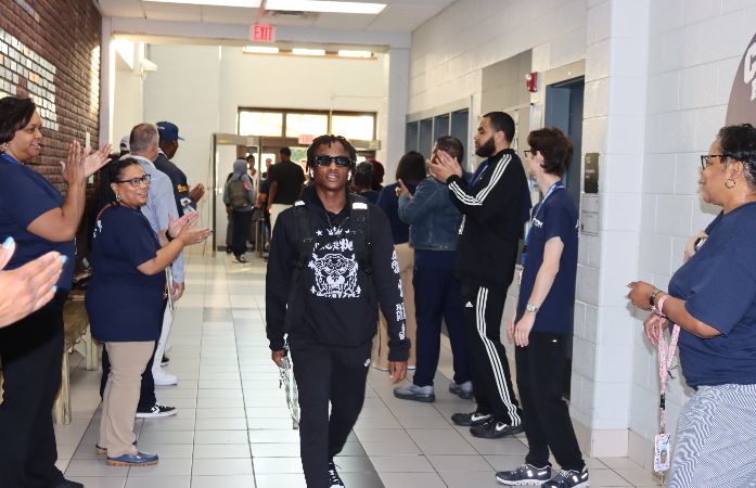  Student walking with sunglasses while people clap