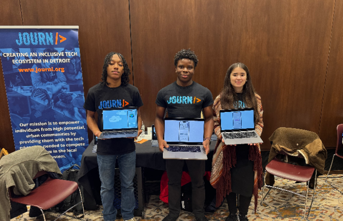  2 boys and 1 girl holding a laptop with black shirt with orange letters.