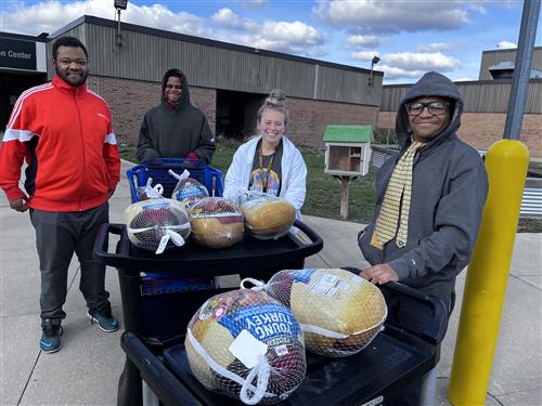 Teacher and students standing with frozen turkeys
