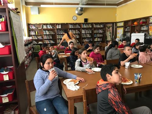 Several students eating pizza and popcorn as a reward for classroom attendance 