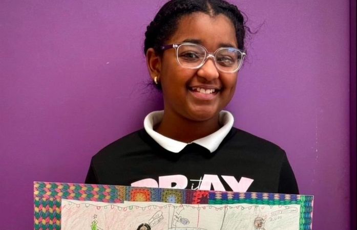   student holding her completed story quilt art project