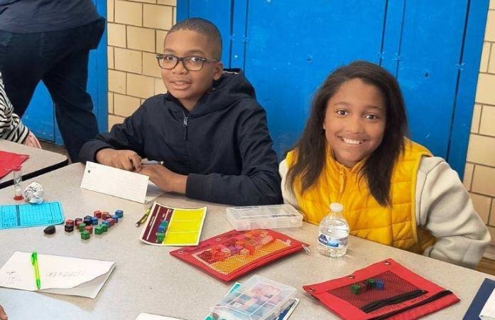  Two students from the Bunche/Chrysler Team smiling while playing Equations at a local tournament