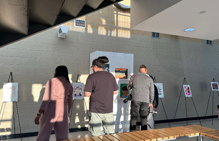  Image of Art Teacher and other district staff viewing the art show with many works on display