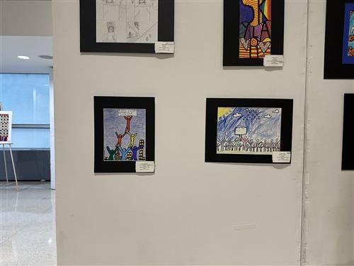Photo of student artworks on display at the exhibit. Both are vibrant drawings showing kids collaborating to make an impact.