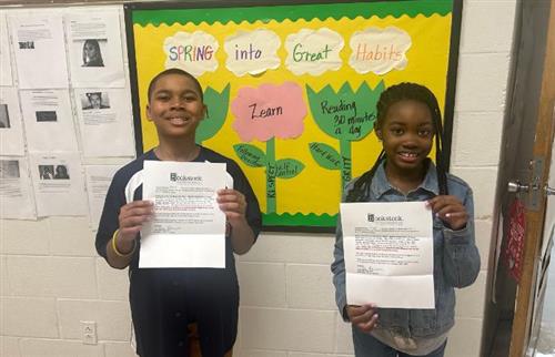  Two students holding their acceptance letters stating they were finalists in the contest