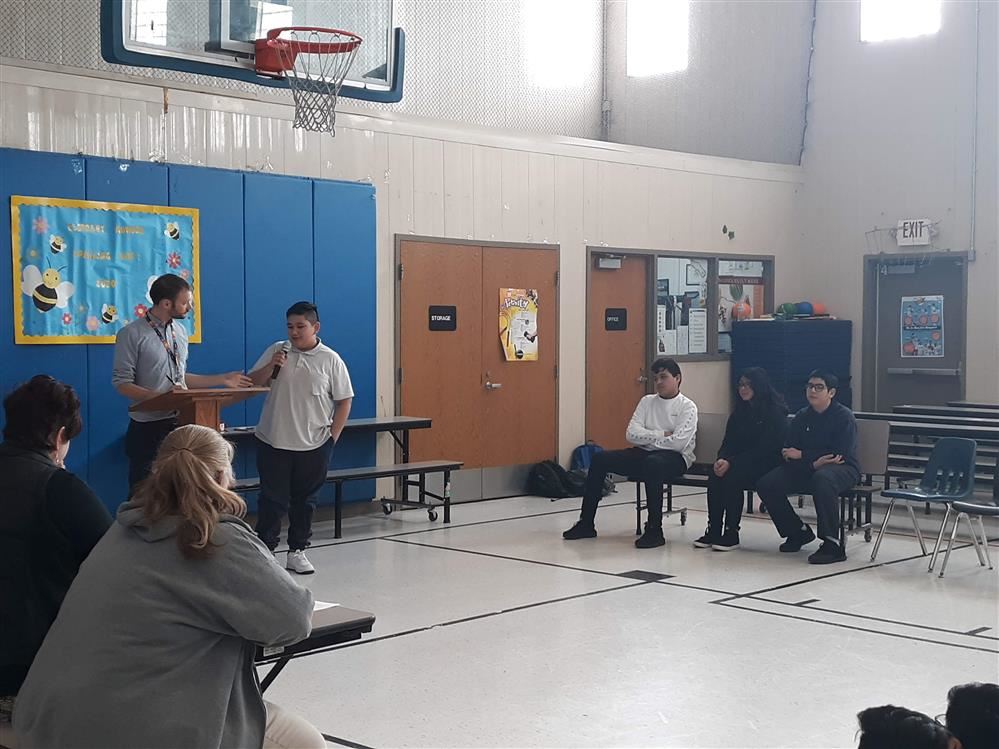  students participating in the spelling bee while a teacher tells the word