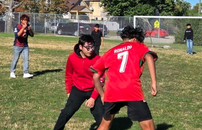  two students near the front playing soccer with 5 other students in the background
