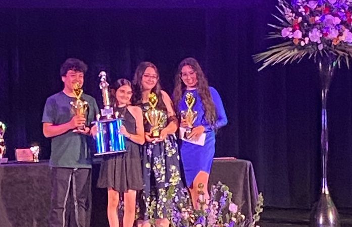 4 students standing together with trophies