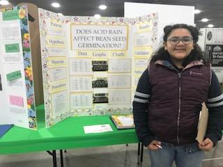 Natalia Garcia and her "Does Acid Rain Affect Bean Seed Germination?" science fair project board.  