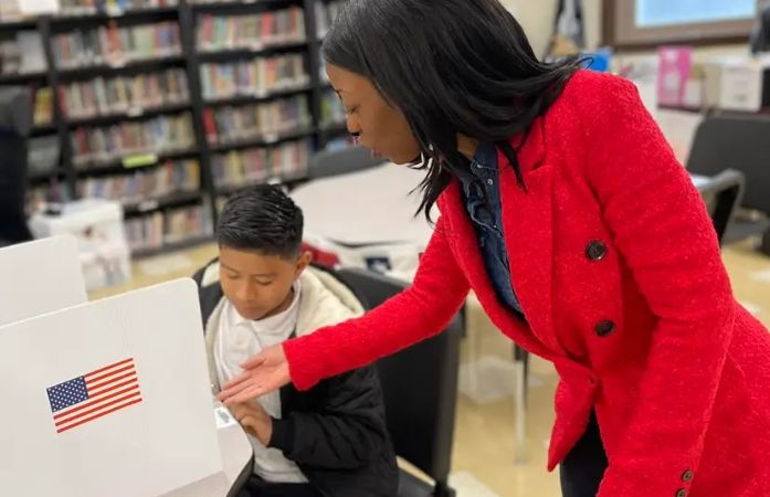 school counselor instructing student about voting ballot at a table