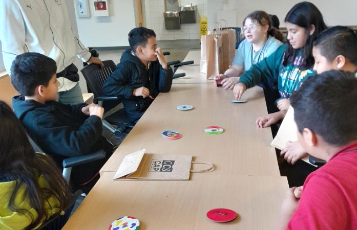  students sitting at a table playing with fidget spinners