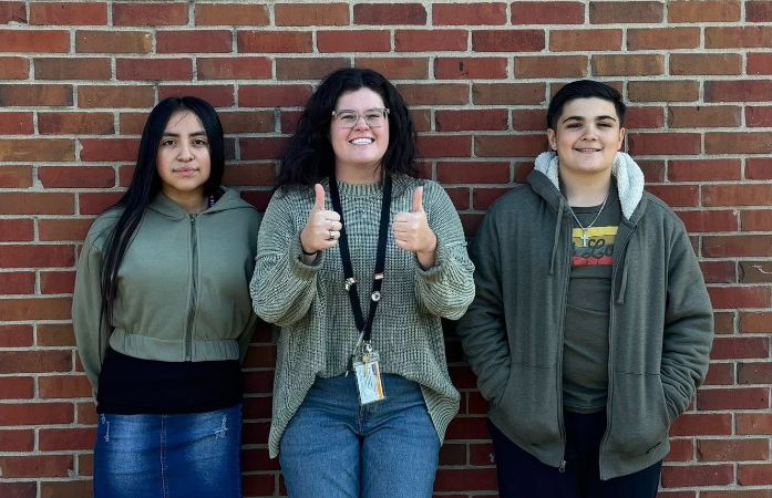 two students and a staff member wearing green