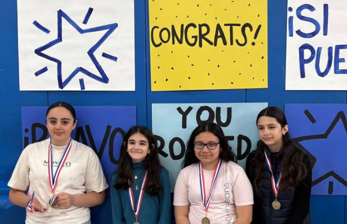  four students standing in front of congratulatory signs
