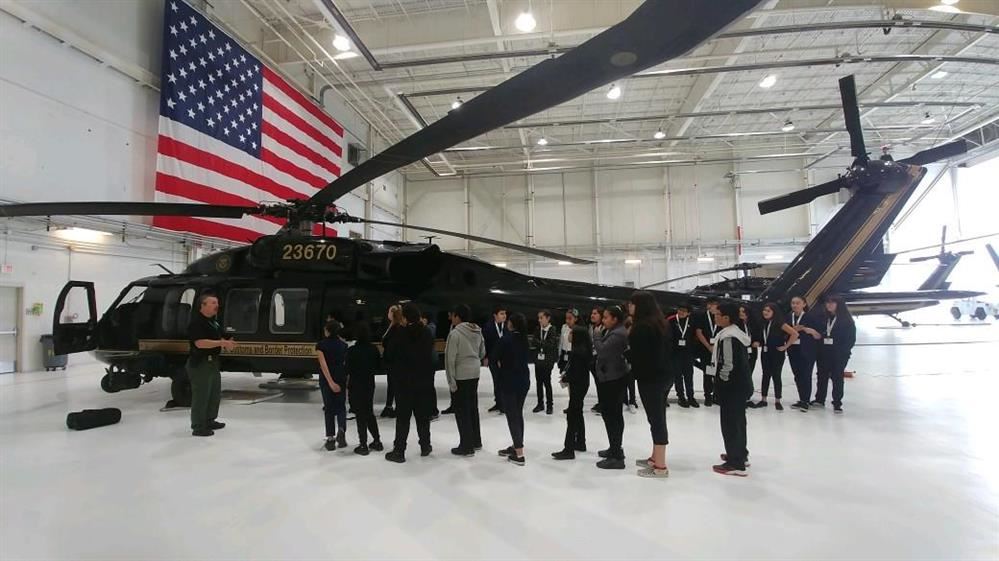  students and an adult standing in front of a helicopter