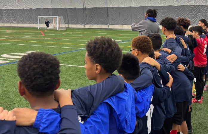  soccer players linking arms at fieldhouse