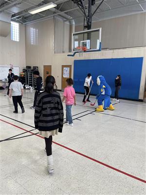 students and eagle mascot playing hockey
